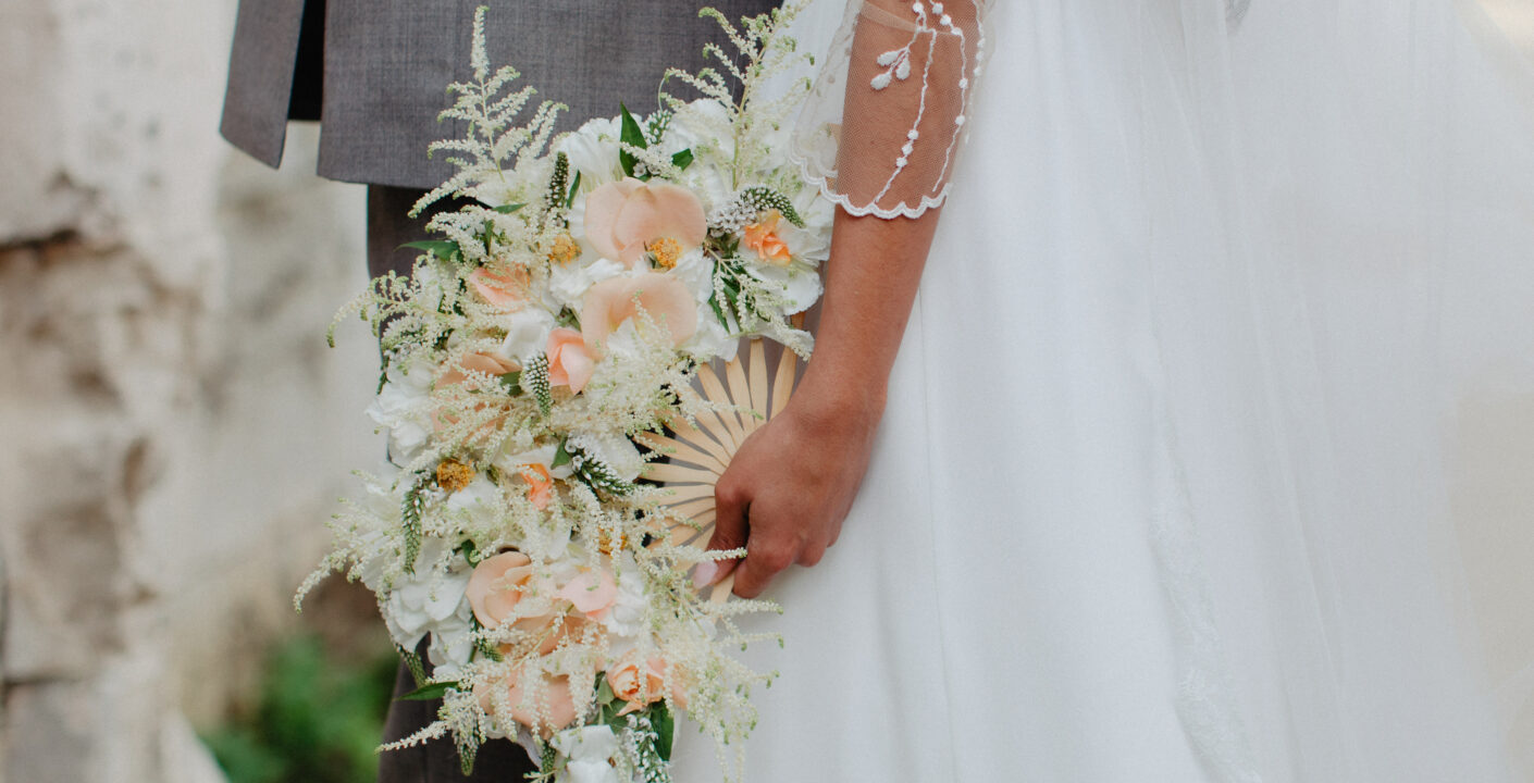 A bride holding an aesthetic flowery fan in her hand
