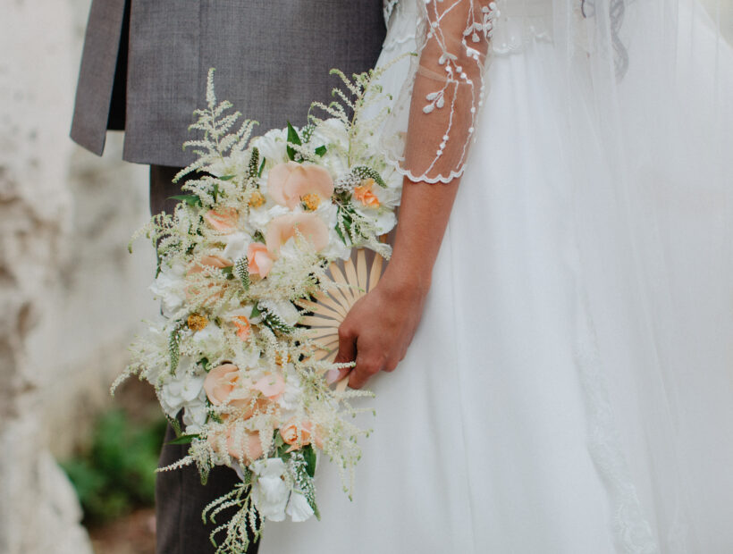 A bride holding an aesthetic flowery fan in her hand