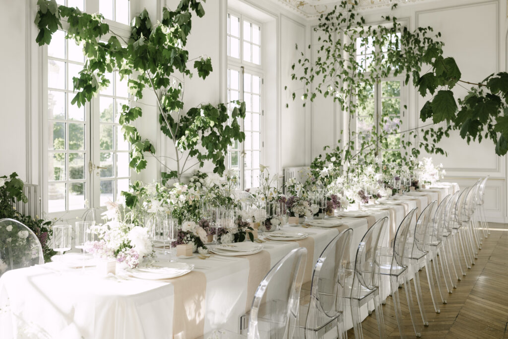 Opulent wedding dinner setup in château ballroom with lilac, columbines and peonies, styled like a garden indoors in a Paris destination wedding.