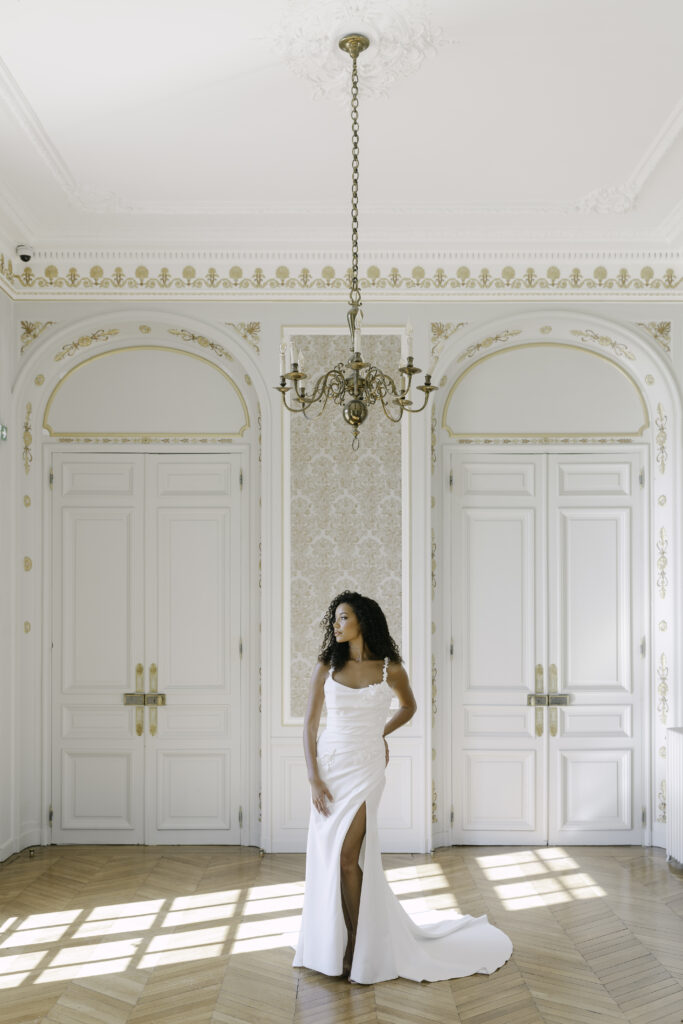 Bride standing gracefully in the salon of a French château near Paris, wearing her wedding dress and ready for the reception.