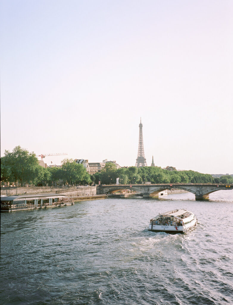 Elegant sightseeing boat cruising along the Seine River with the Eiffel Tower in the background, capturing the timeless romance of a Paris destination wedding.